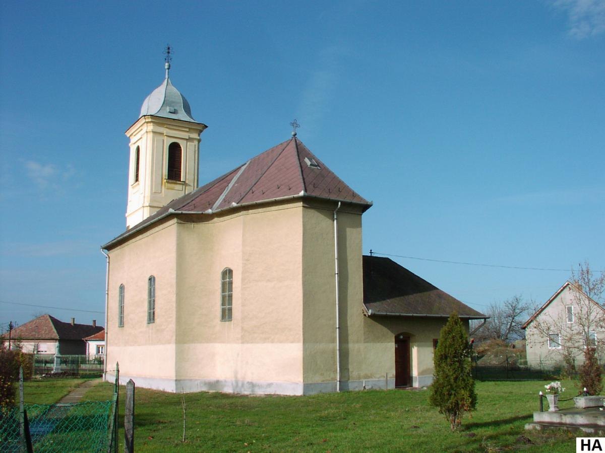 A tarnabodi Szent István király templom: sárga falú barokk templom hagymasisakos toronnyal, előtte füves templomkert